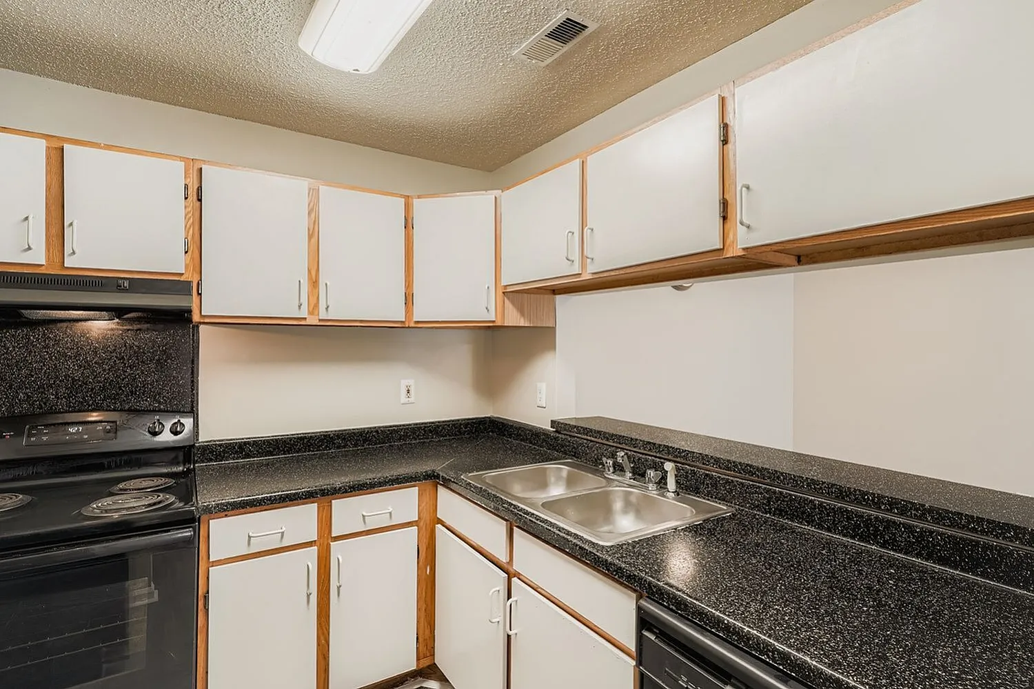 Kitchen, wood-frame white cabinetry, black speckled countertops, black electric range