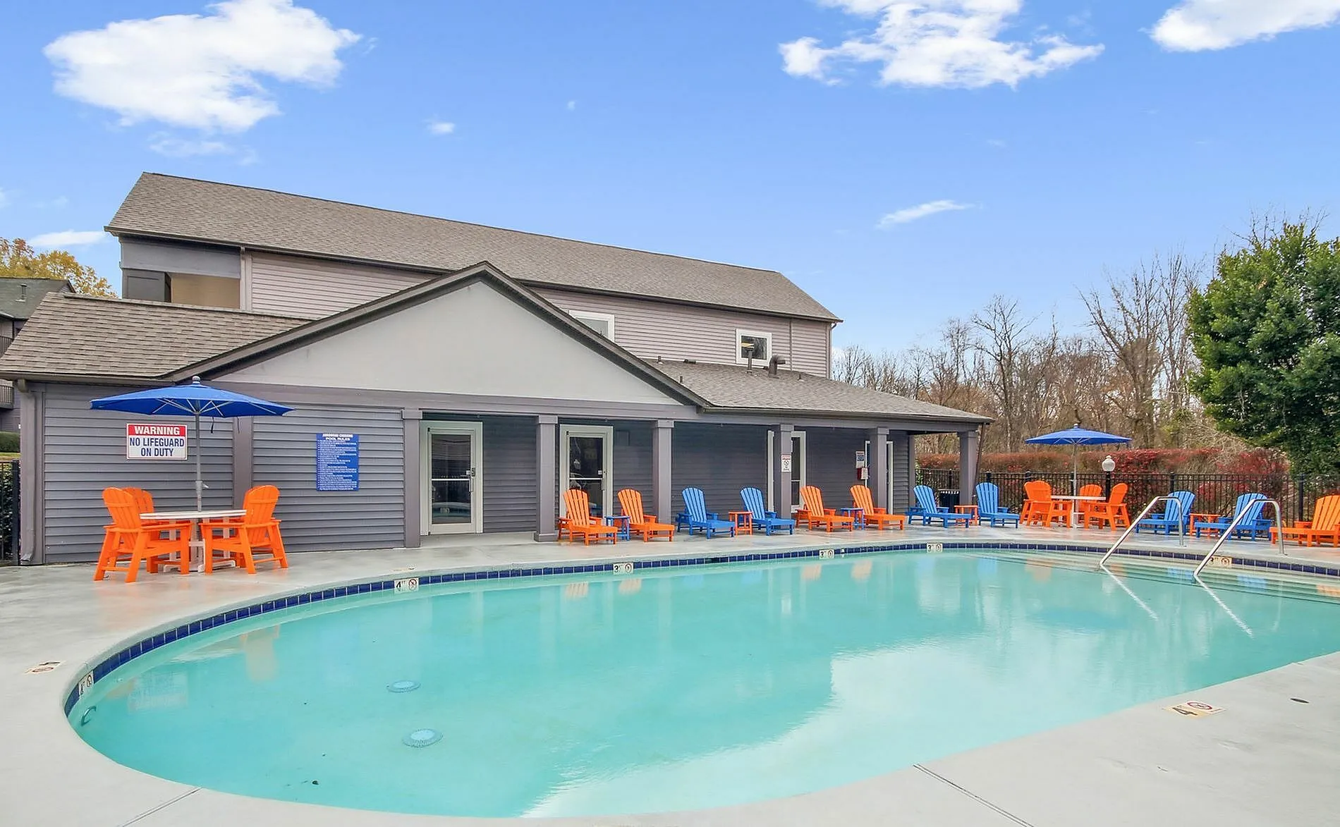 Community pool, turquoise water, orange lounge chairs, blue umbrellas, clubhouse