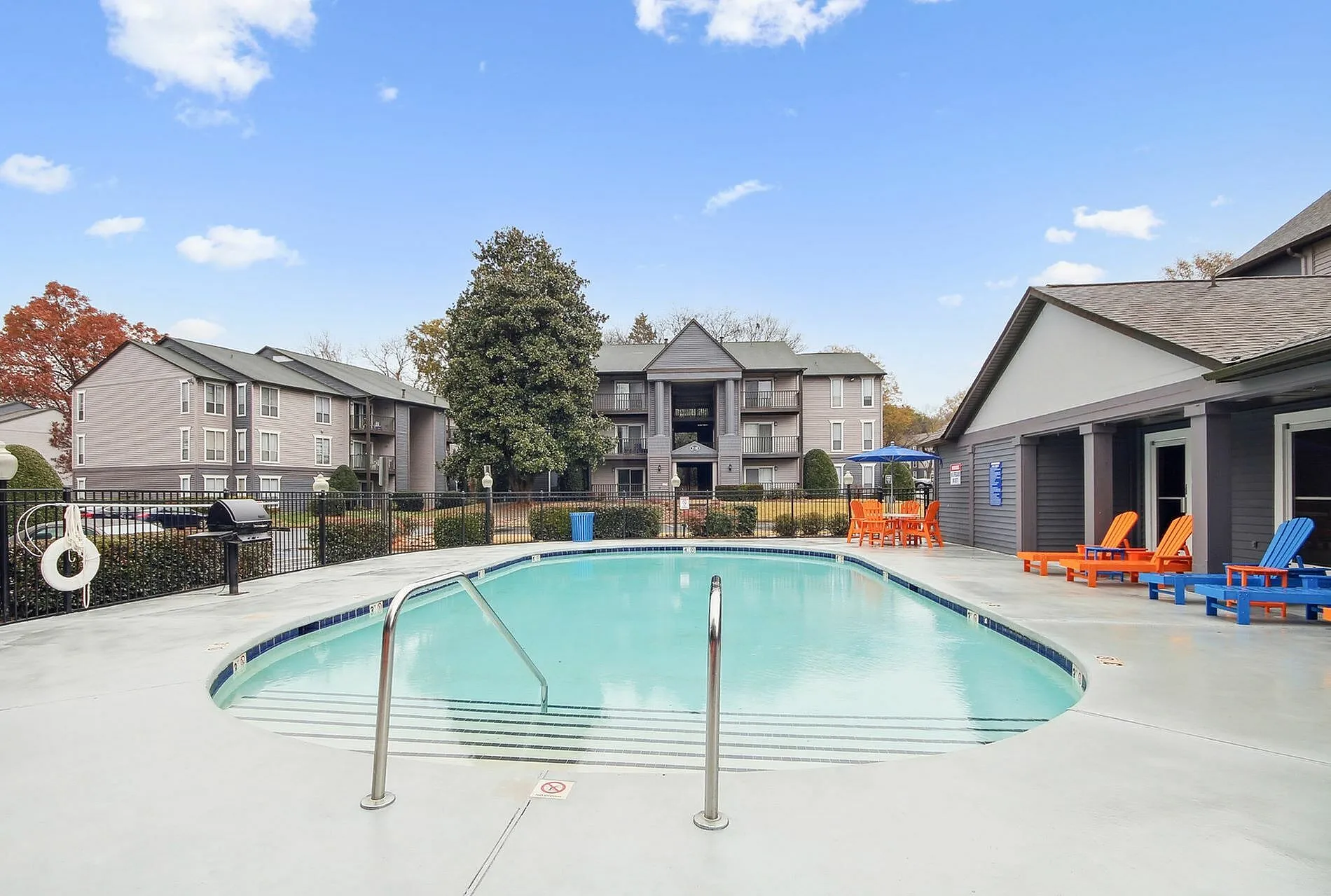 Resort-style pool, lounge seating, multi-story apartment buildings, landscaping