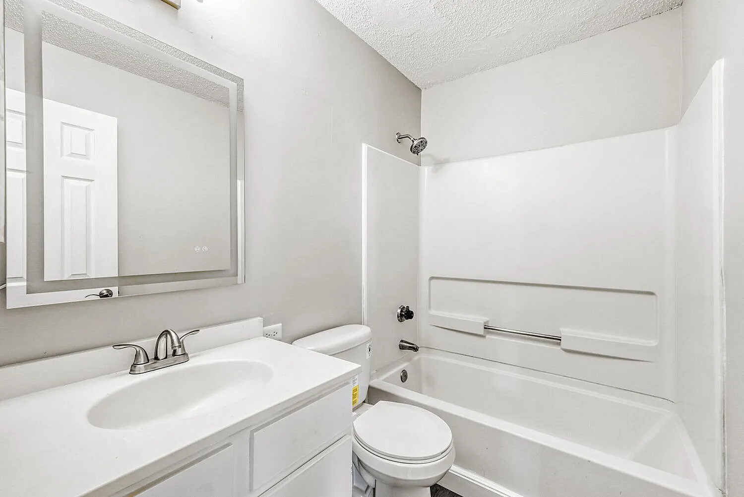 Bathroom, white vanity with sink, framed mirror, white subway tile tub surround, toilet