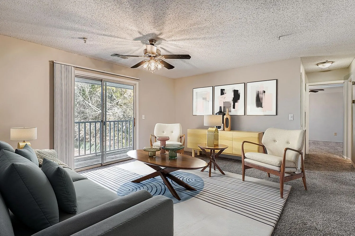 Living room, wood-style plank flooring, ceiling fan, glass balcony doors, neutral seating