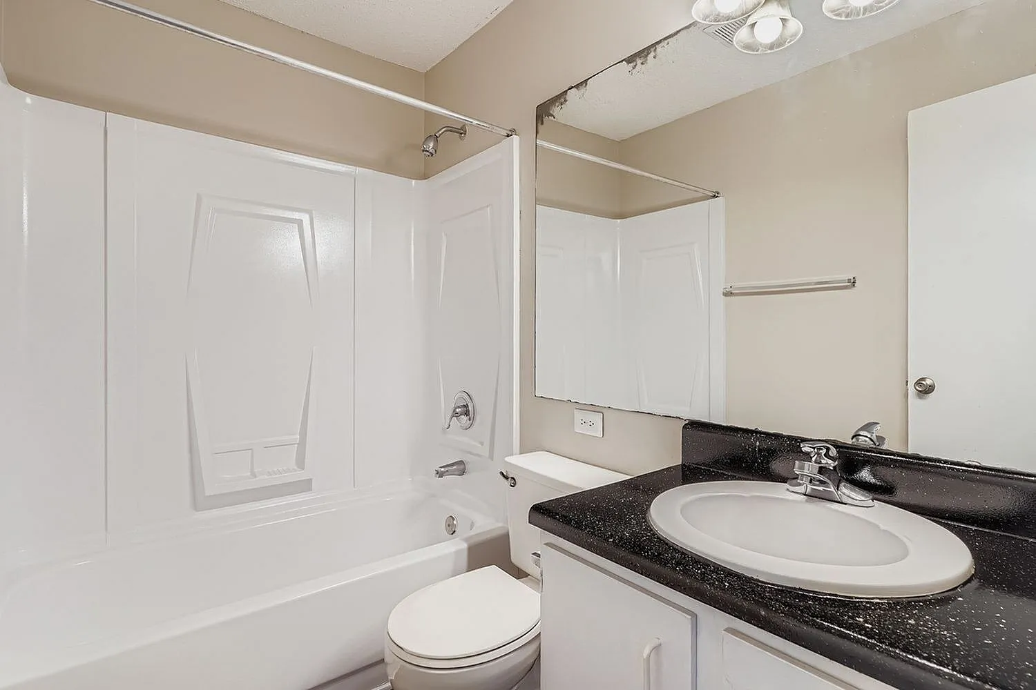Bathroom, black speckled countertop, white oval sink, white cabinetry, toilet