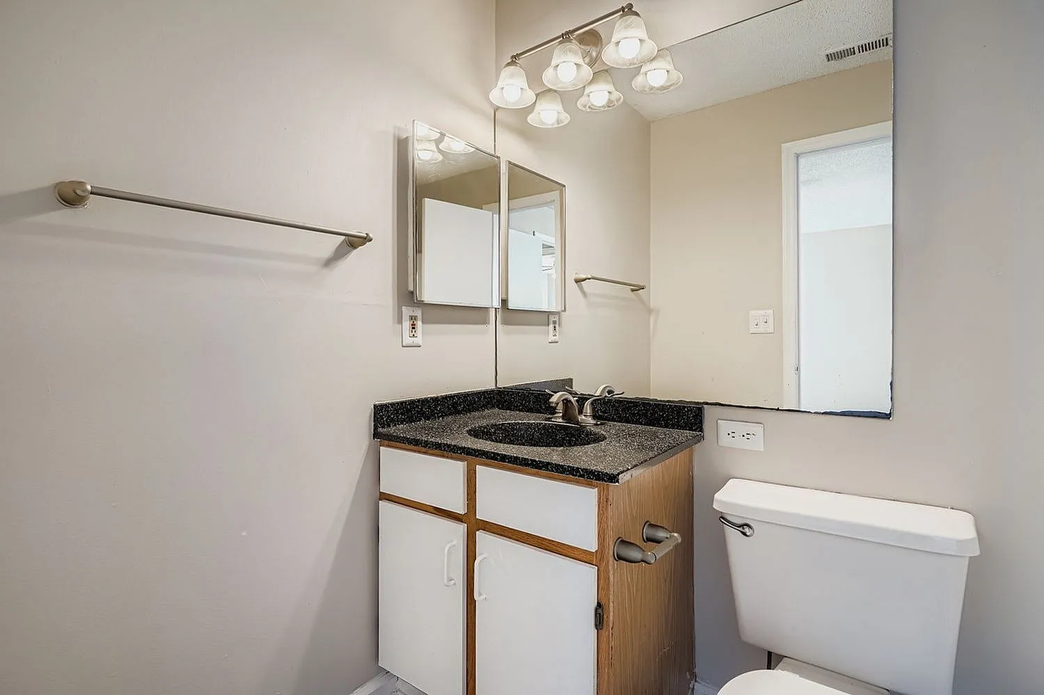 Primary bathroom, granite countertops, white vanity, mirrored medicine cabinet, brushed nickel fixtures