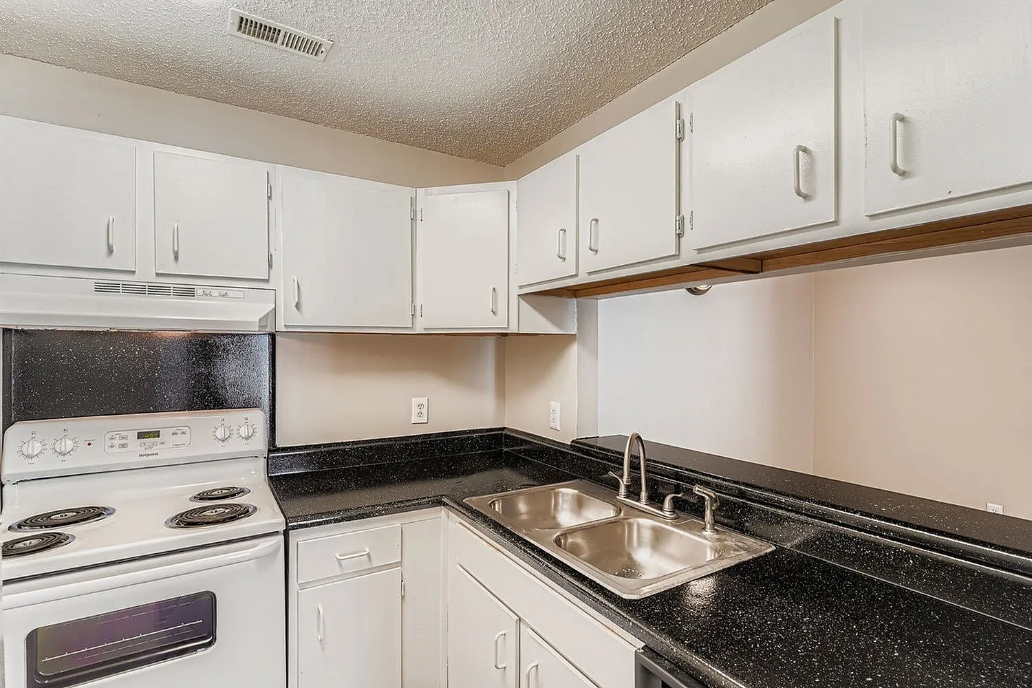 Kitchen, white cabinetry, black speckled countertops, dual sink, white coil stove