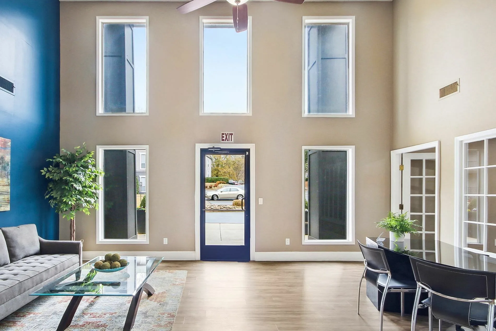 Leasing lounge, wood-style plank flooring, multiple glass doors and windows, blue accent wall, seating areas