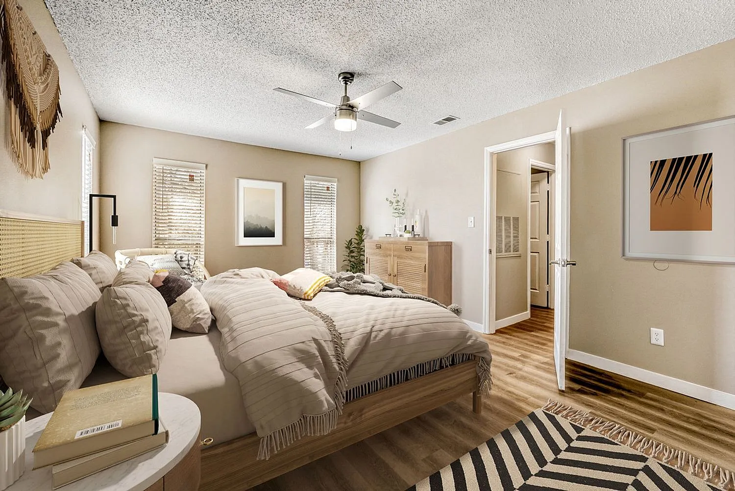 Primary bedroom, wood-style plank flooring, ceiling fan, striped area rug, en-suite bathroom