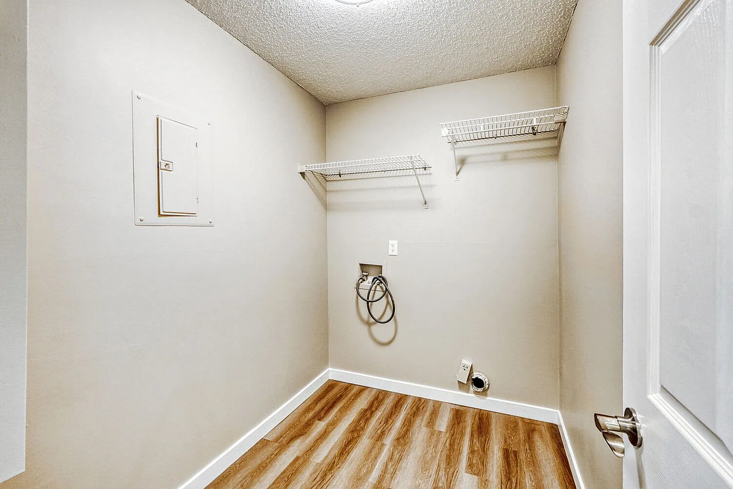 Laundry room, wood-style plank flooring, wire shelving, white walls, outlet