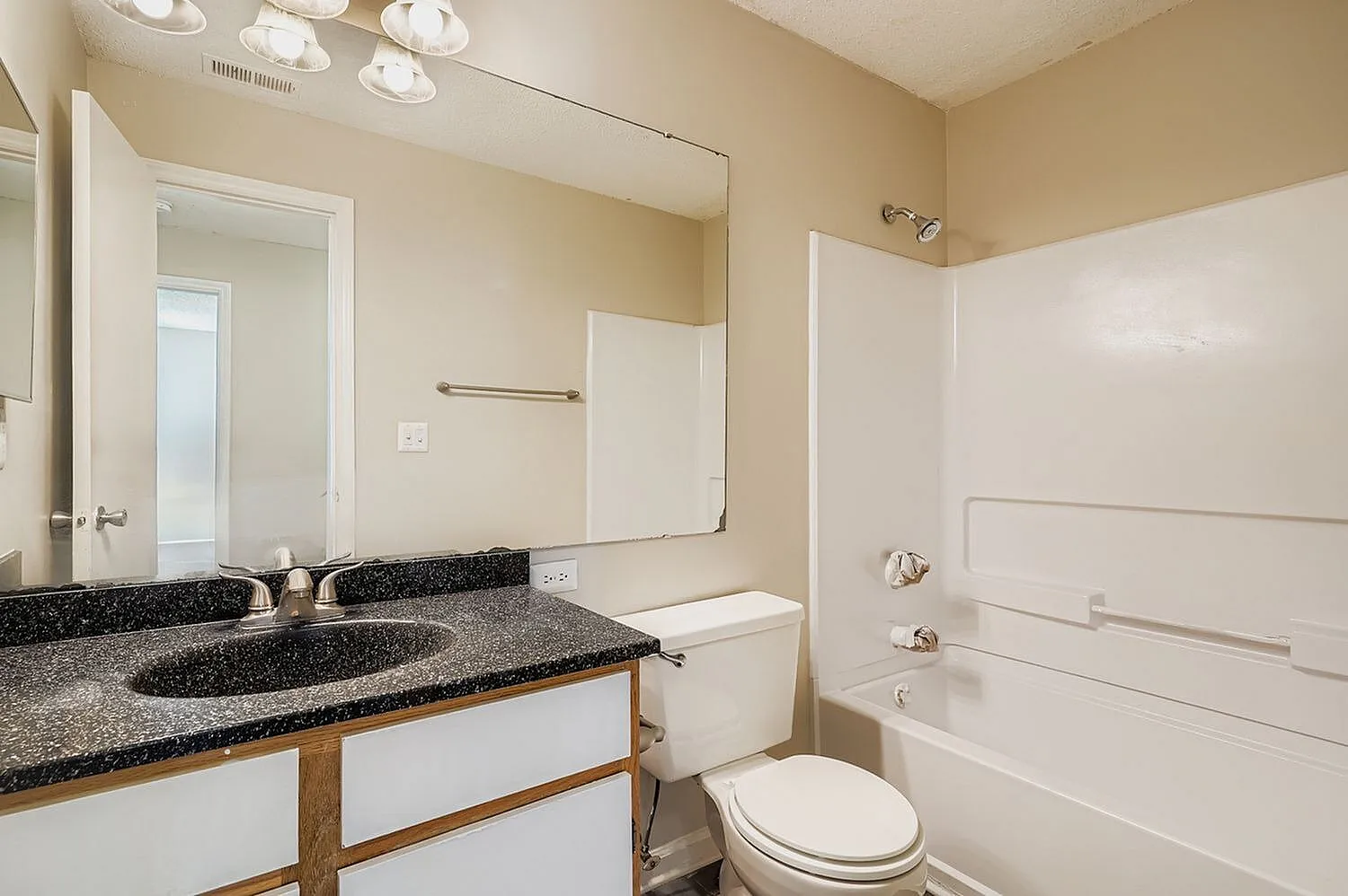 Primary bathroom, speckled gray countertops, round sink, white cabinetry, large mirror