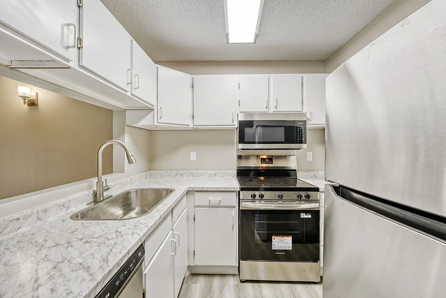Kitchen, white shaker cabinetry, marble countertops, stainless appliances, wood-style plank flooring