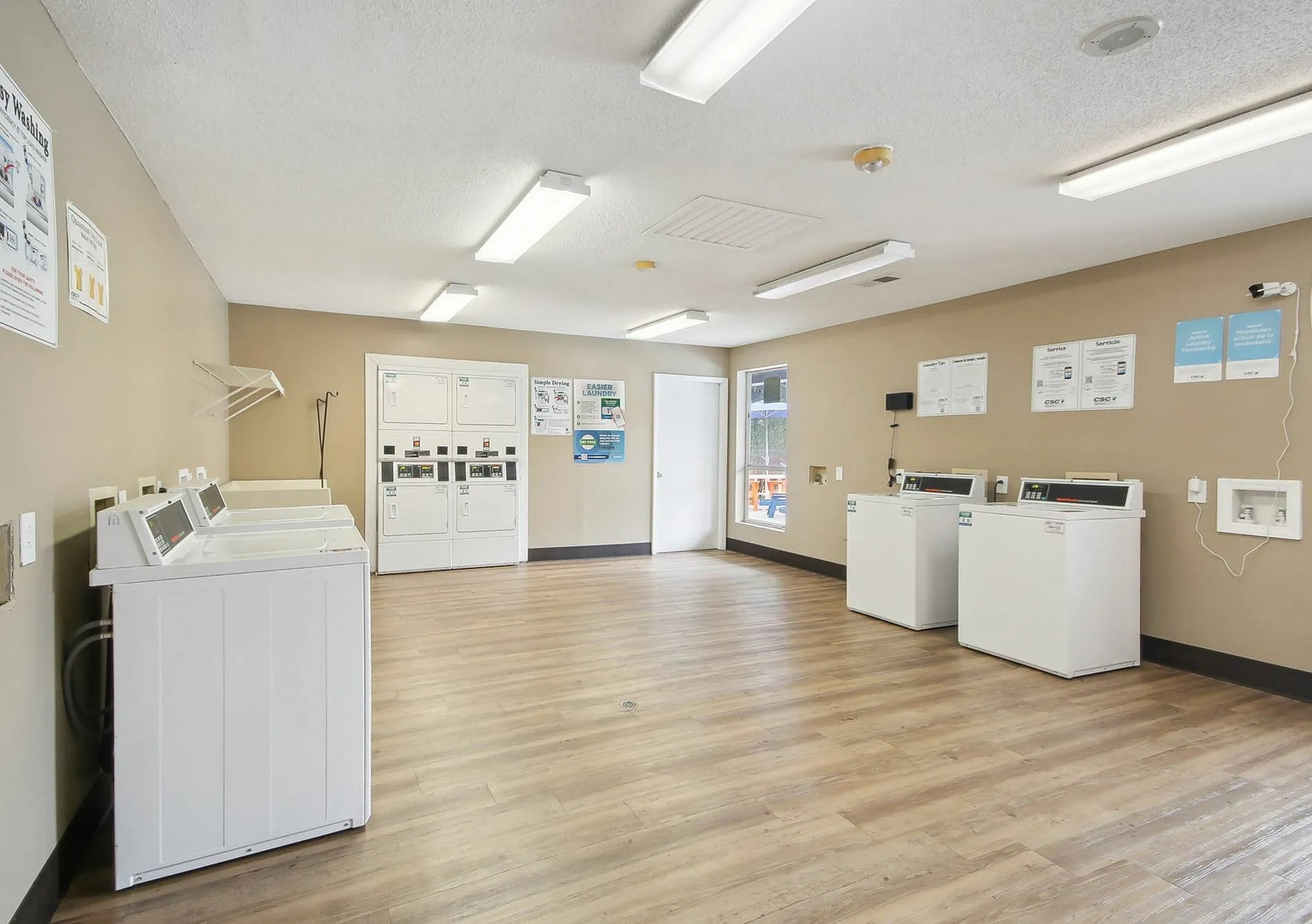 Laundry room, white front-load washers and dryers, wood-style plank flooring, bulletin board