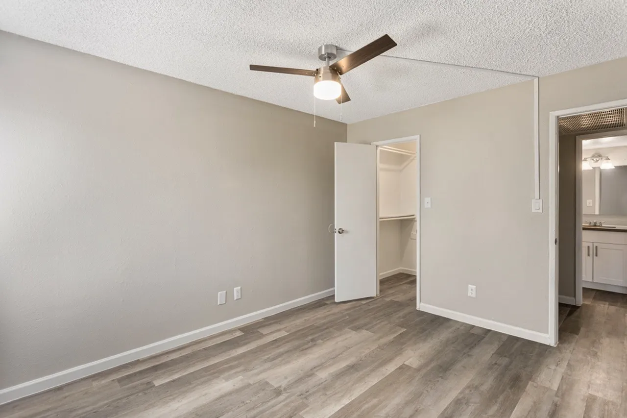 Bedroom, wood-style plank flooring, ceiling fan with light, open closet, en-suite bathroom