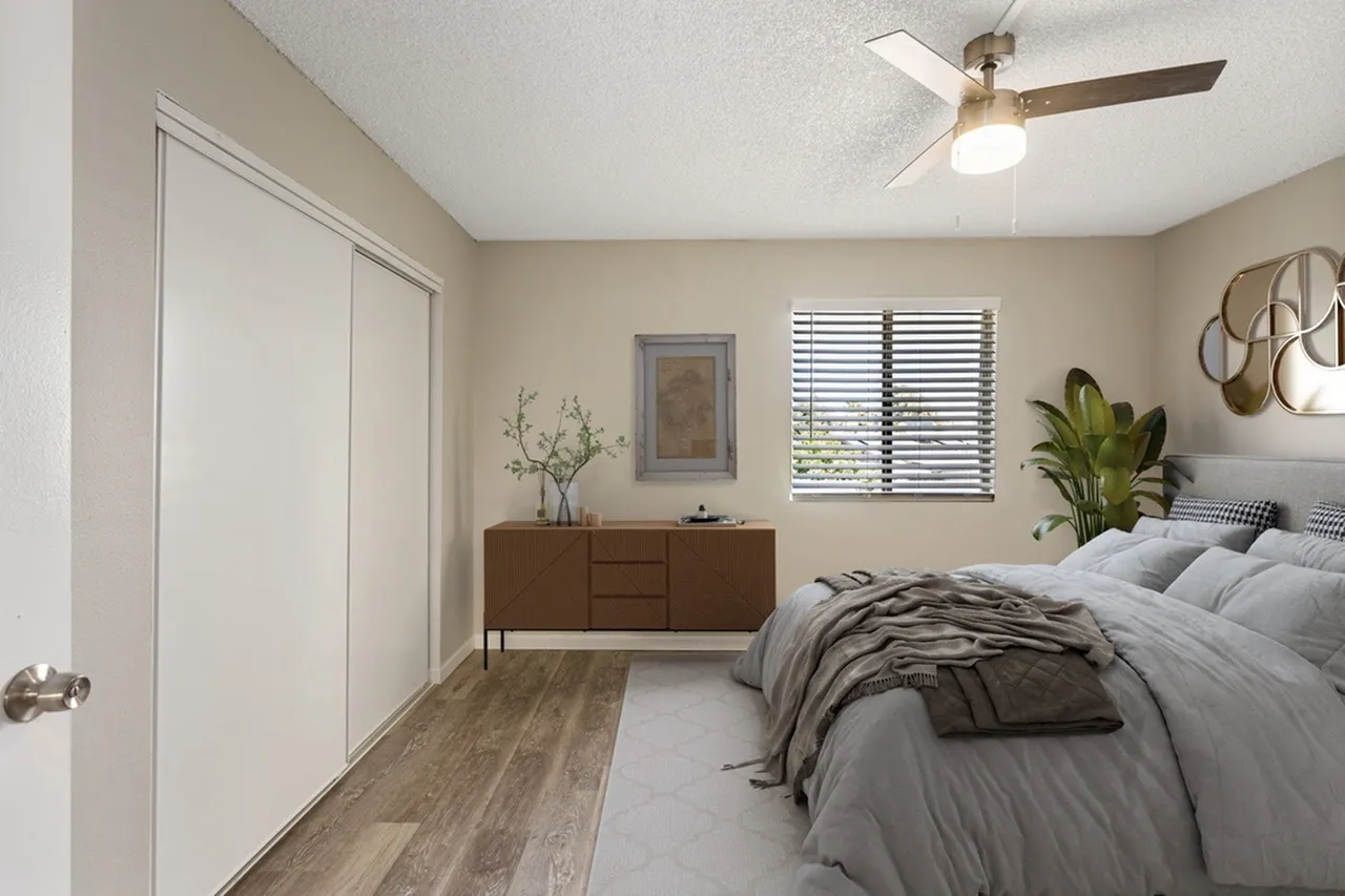 Primary bedroom, wood-style plank flooring, ceiling fan, wood dresser, plantation shutters
