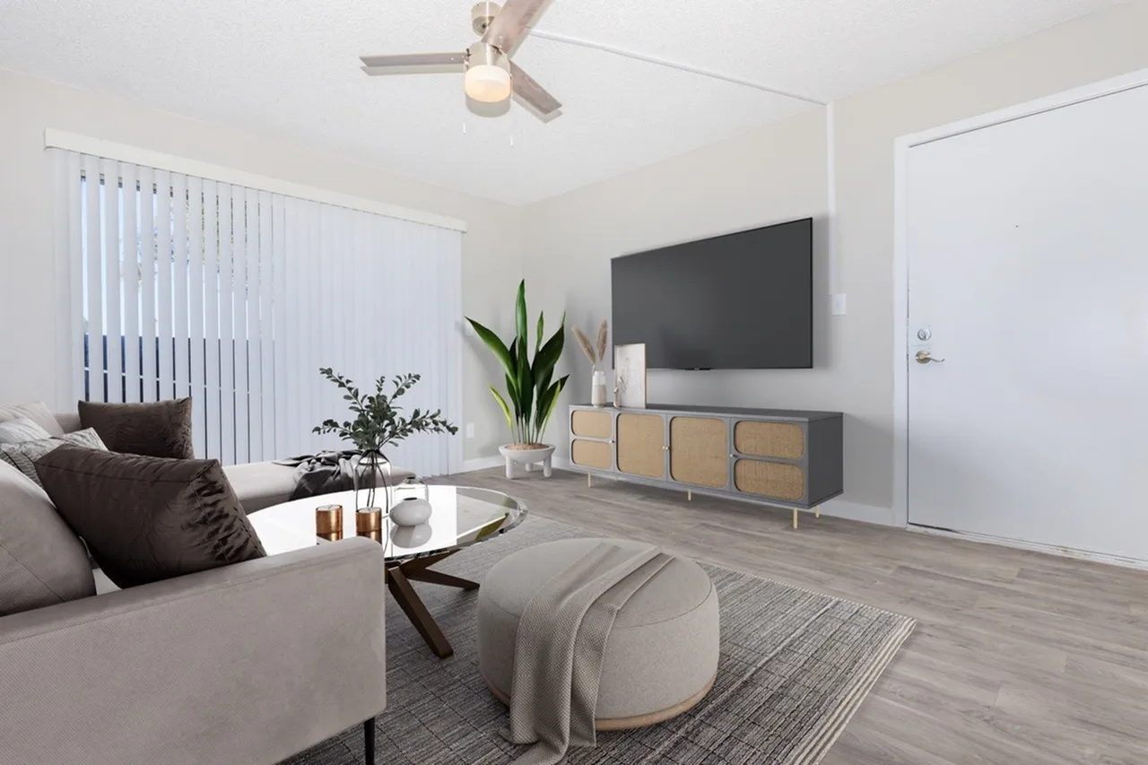 Living room, wood-style plank flooring, ceiling fan, wall-mounted TV, natural light from windows