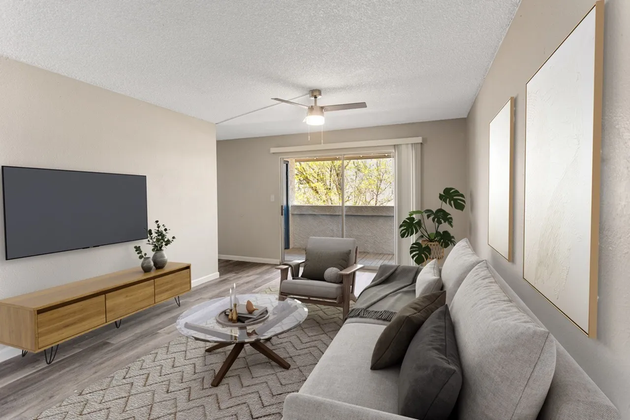 Living room with light gray sofa, wood-style plank flooring, flat-screen TV, ceiling fan