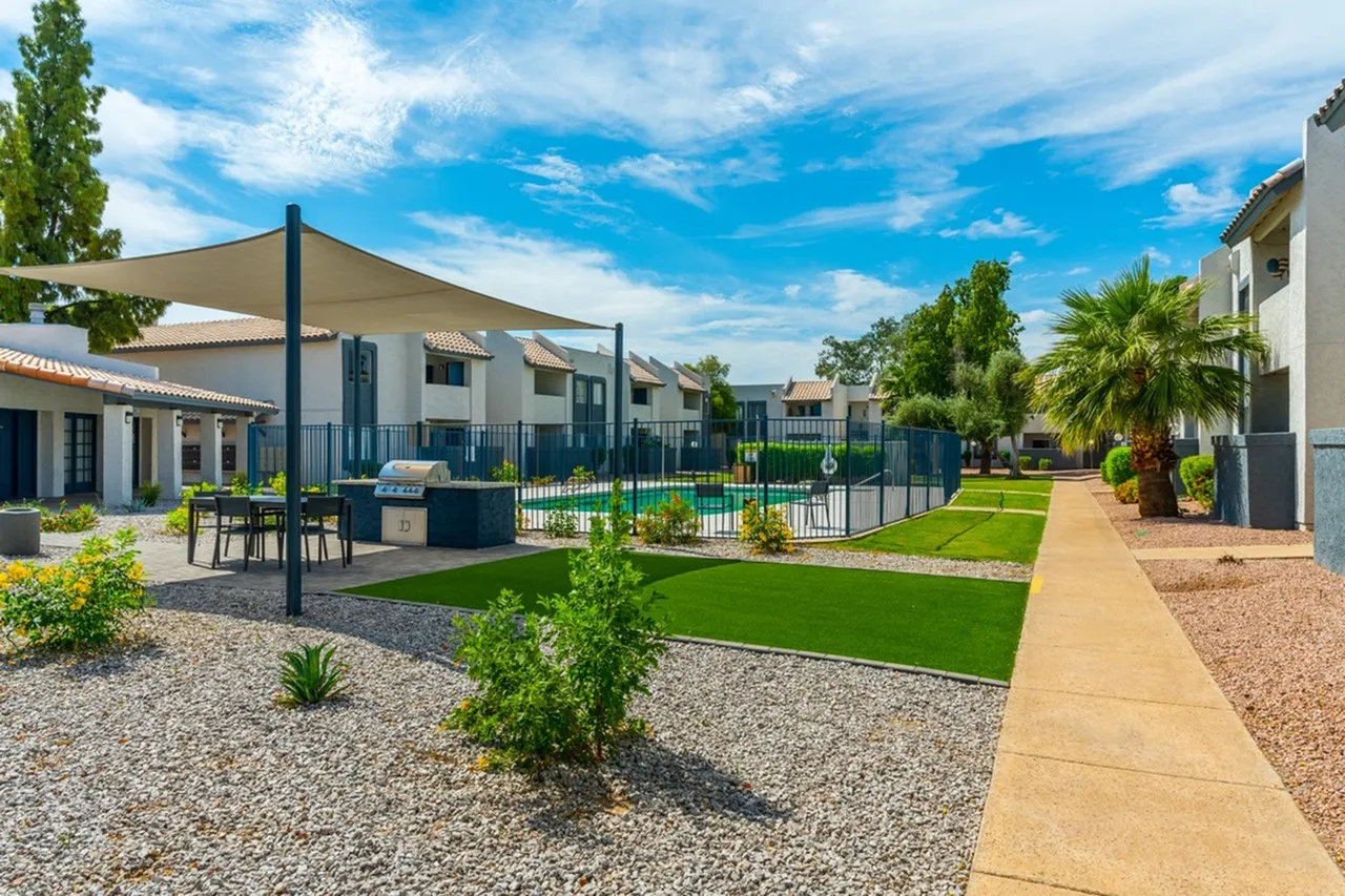 Courtyard with shade structure, seating area, pool with fencing, manicured lawn, architectural landscaping