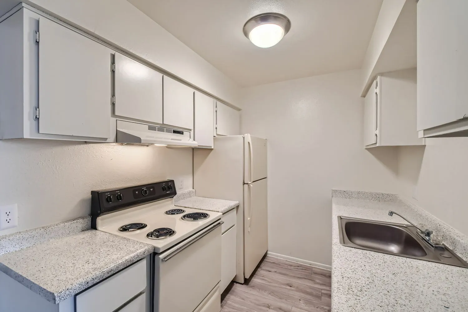 Kitchen, white cabinetry, quartz countertops, black coil range, stainless refrigerator, wood-style plank flooring