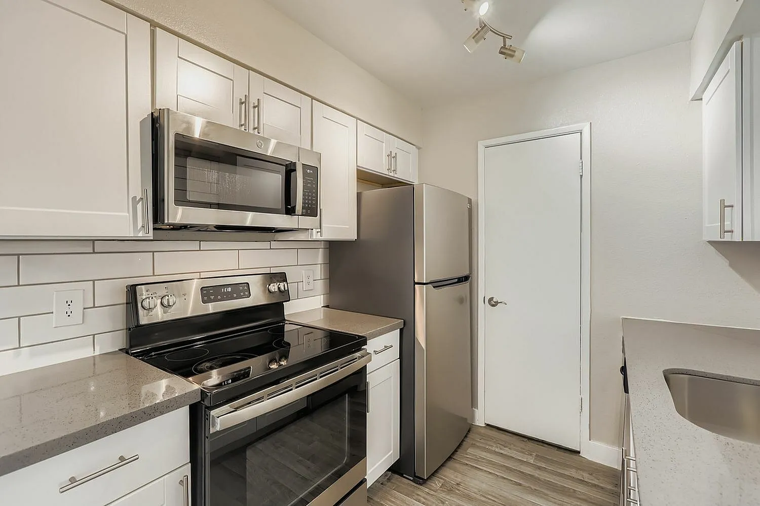 Kitchen, white shaker cabinetry, quartz countertops, stainless appliances, subway tile backsplash, wood-style plank flooring