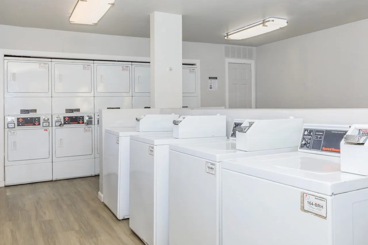 Laundry room, white washers and dryers, wood-style plank flooring, fluorescent ceiling lights