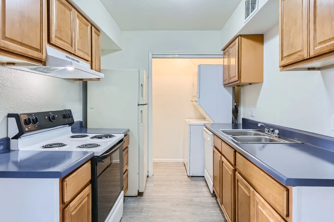 Kitchen, wood cabinetry, blue countertops, electric range, stainless sink, wood-style plank flooring