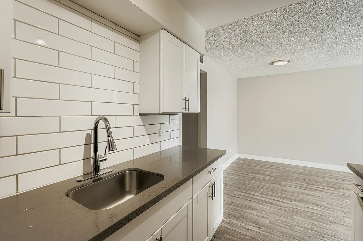 Kitchen, white shaker cabinetry, gray quartz countertops, subway tile backsplash, stainless steel sink, wood-style plank flooring