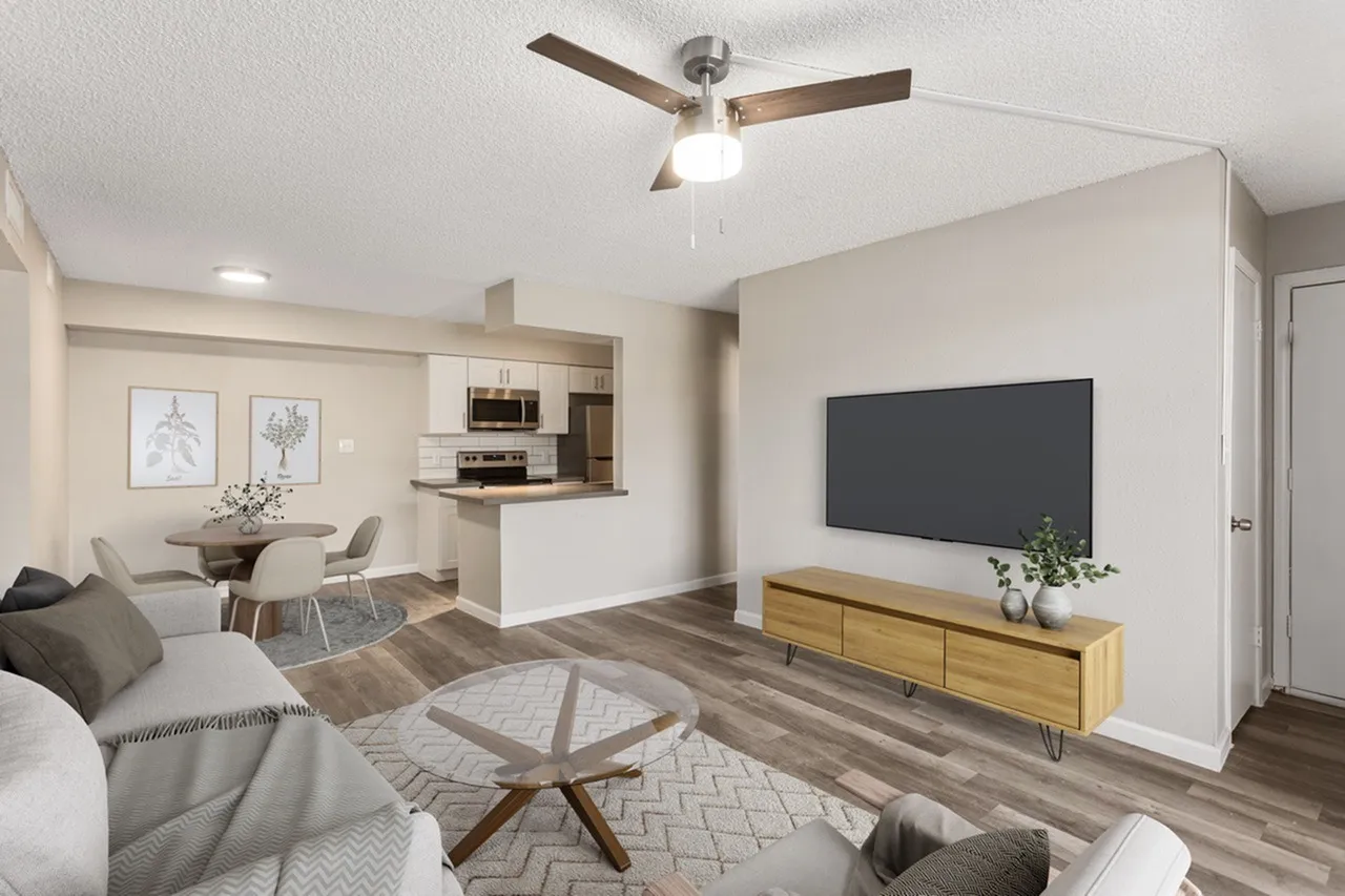 Open floor plan living room and kitchen, wood-style plank flooring, ceiling fan with light fixture, flat-screen TV