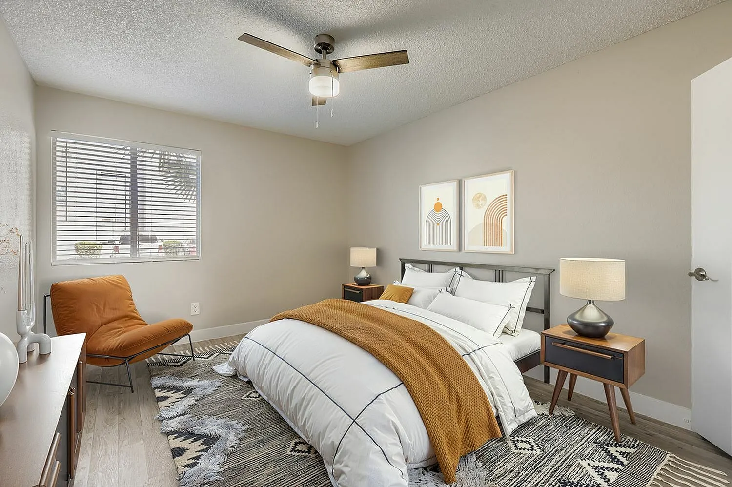 Primary bedroom, wood-style plank flooring, ceiling fan, upholstered bed, nightstands with lamps