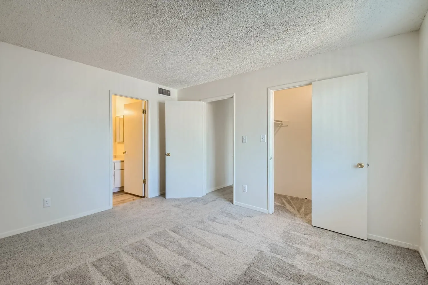 Bedroom, gray striped carpet, wood-style plank flooring, white doors and walls, ensuite bathroom