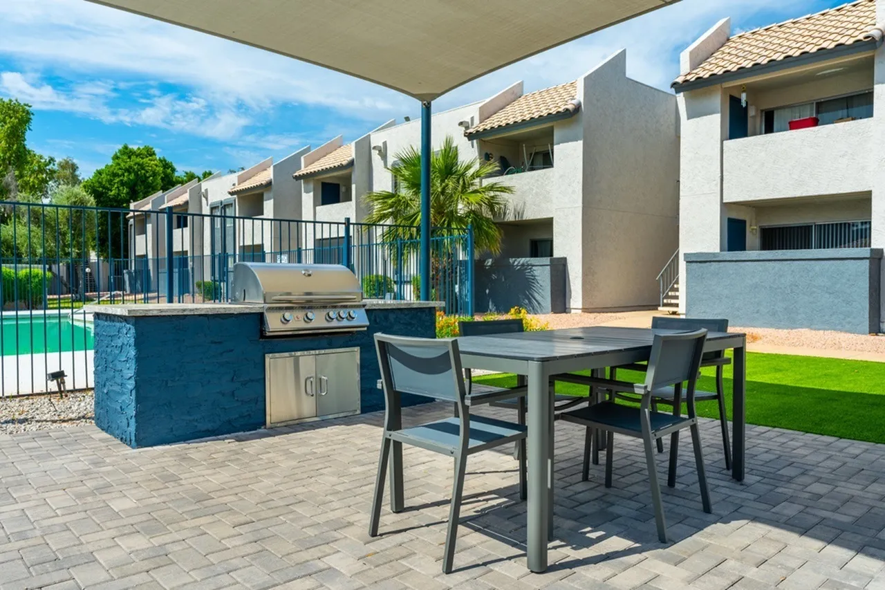 Patio with dining table, blue outdoor kitchen island, grilling station, pool