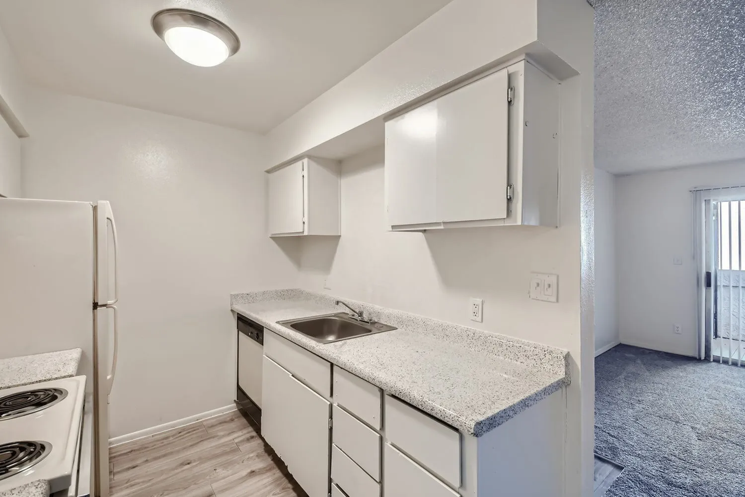 Kitchen, white shaker cabinetry, gray quartz countertops, built-in sink, wood-style plank flooring