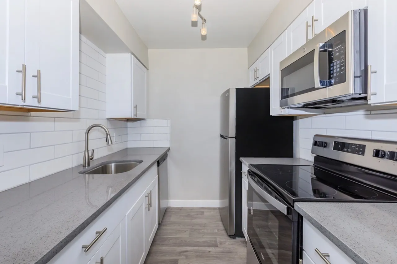 Kitchen, white shaker cabinetry, gray quartz countertops, stainless appliances, subway tile backsplash, wood-style plank flooring