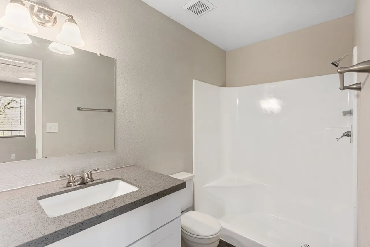 Bathroom, quartz countertops, white undermount sink, chrome faucet, white tile shower enclosure