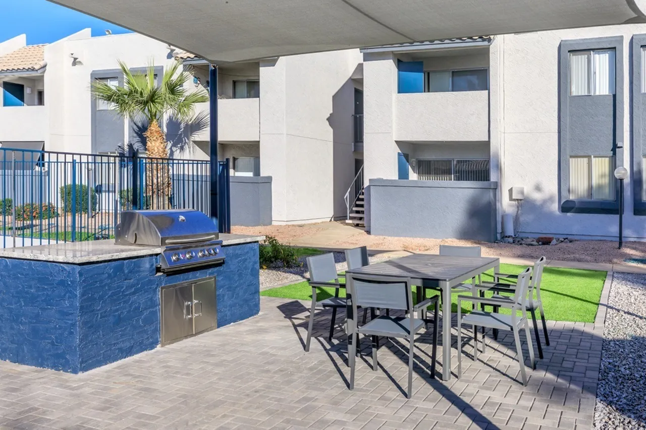 Outdoor patio area, blue built-in grill, dining table with chairs, artificial turf, palm tree