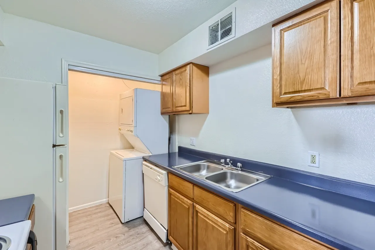 Kitchen, wood cabinetry, blue countertops, stainless double sink, wood-style plank flooring