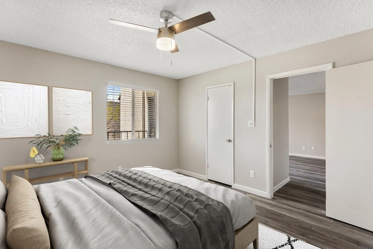 Primary bedroom, wood-style plank flooring, ceiling fan with light, white closet doors