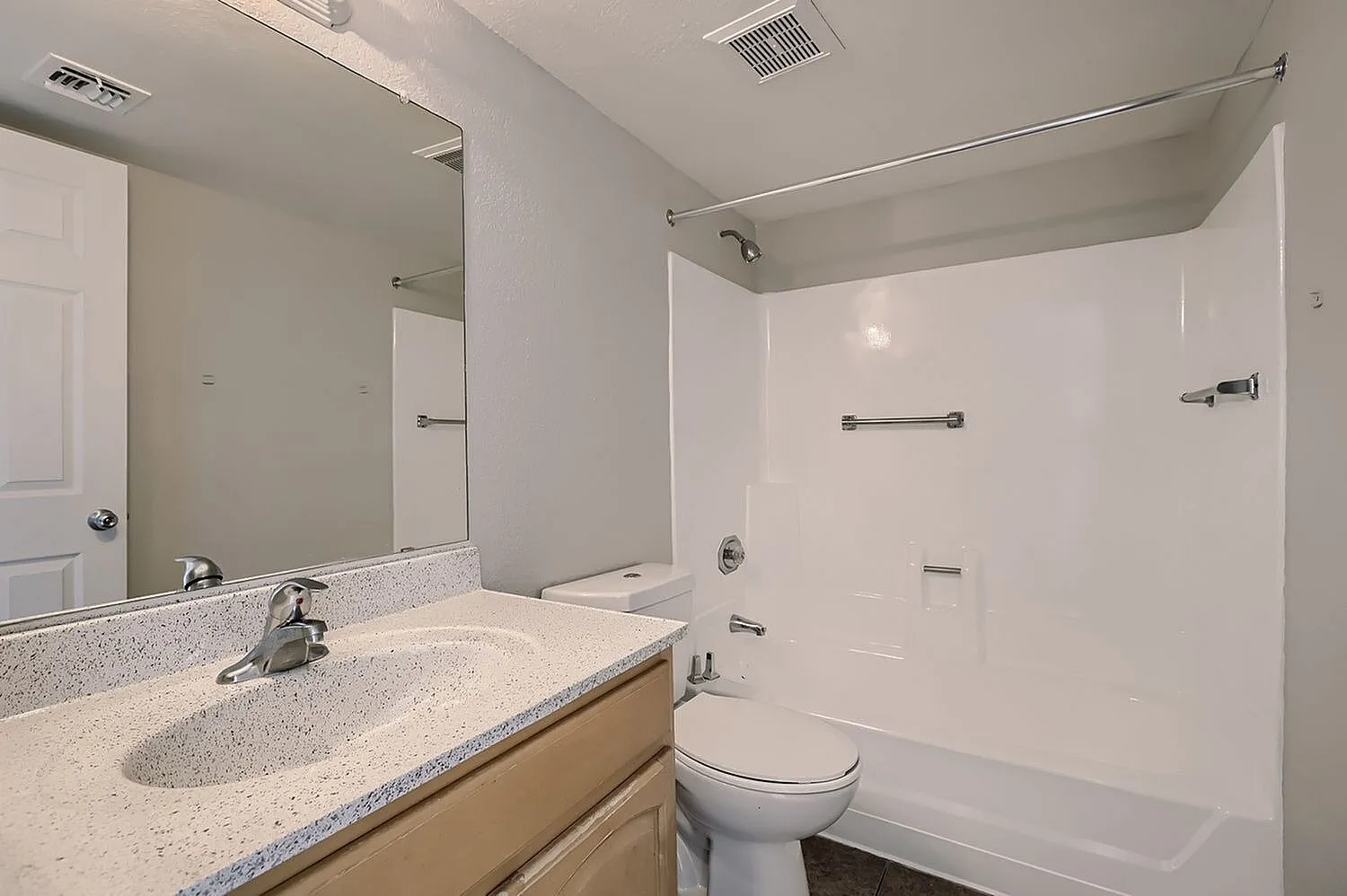 Bathroom, quartz countertop, integrated sink, large mirror, white vanity cabinetry, bathtub with shower enclosure