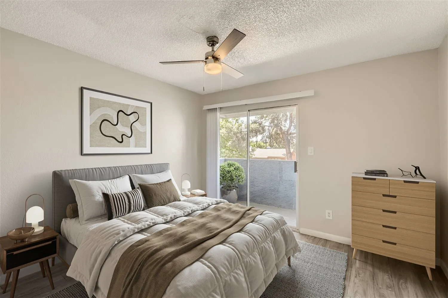 Primary bedroom, wood-style plank flooring, ceiling fan, sliding glass door, wood dresser