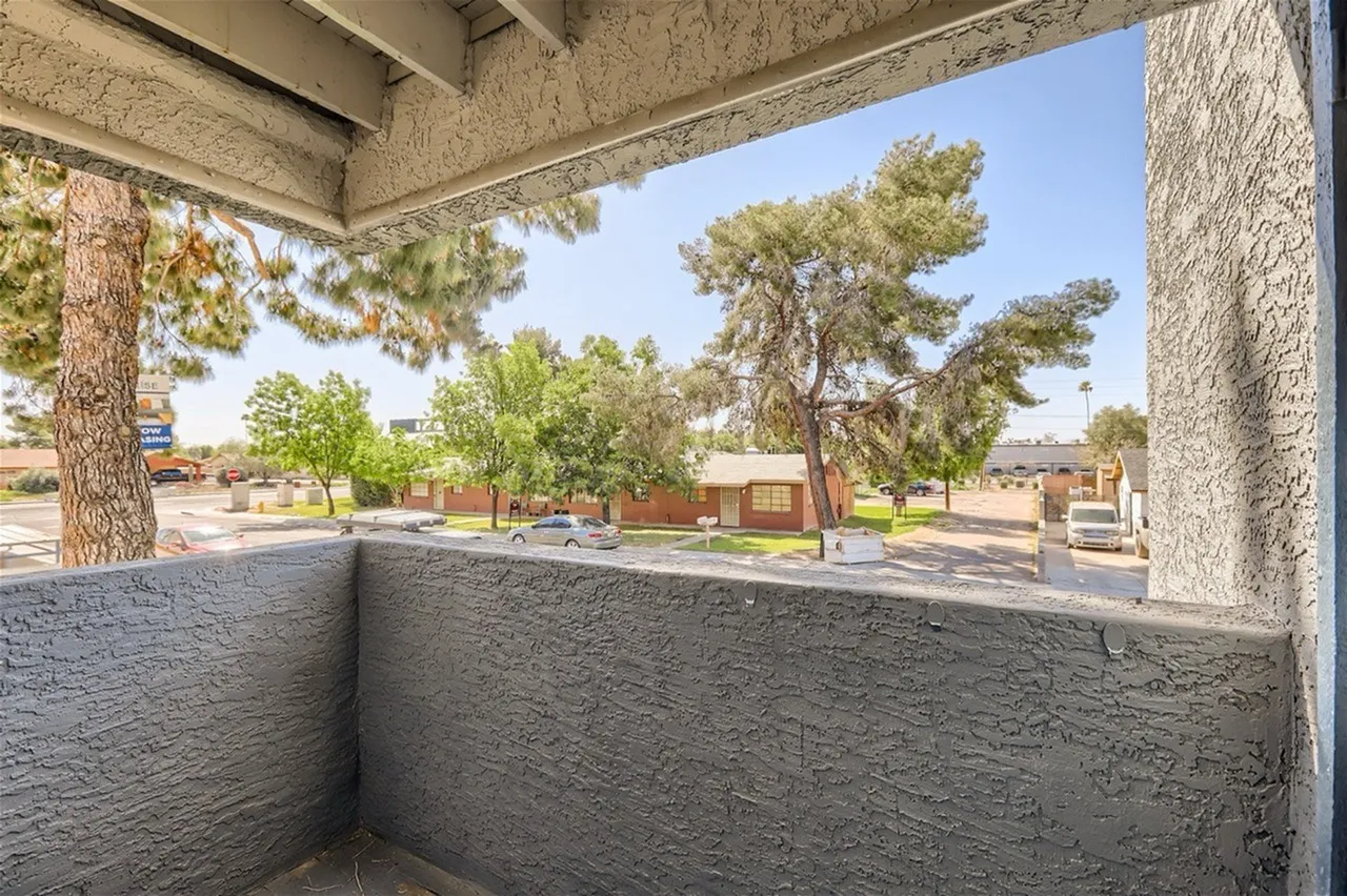 Covered patio, concrete walls, street view with trees and parked cars