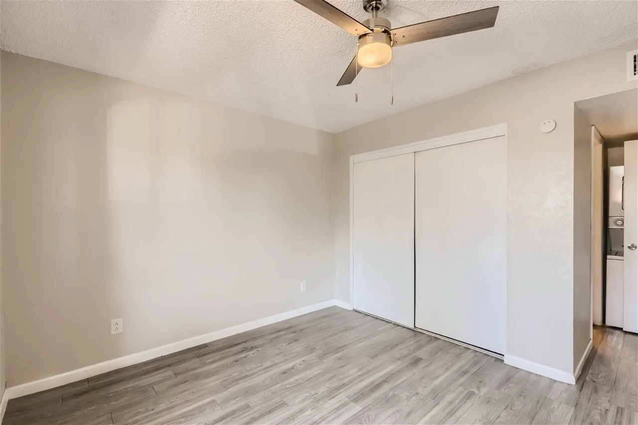 Primary bedroom, wood-style plank flooring, white closet doors, ceiling fan