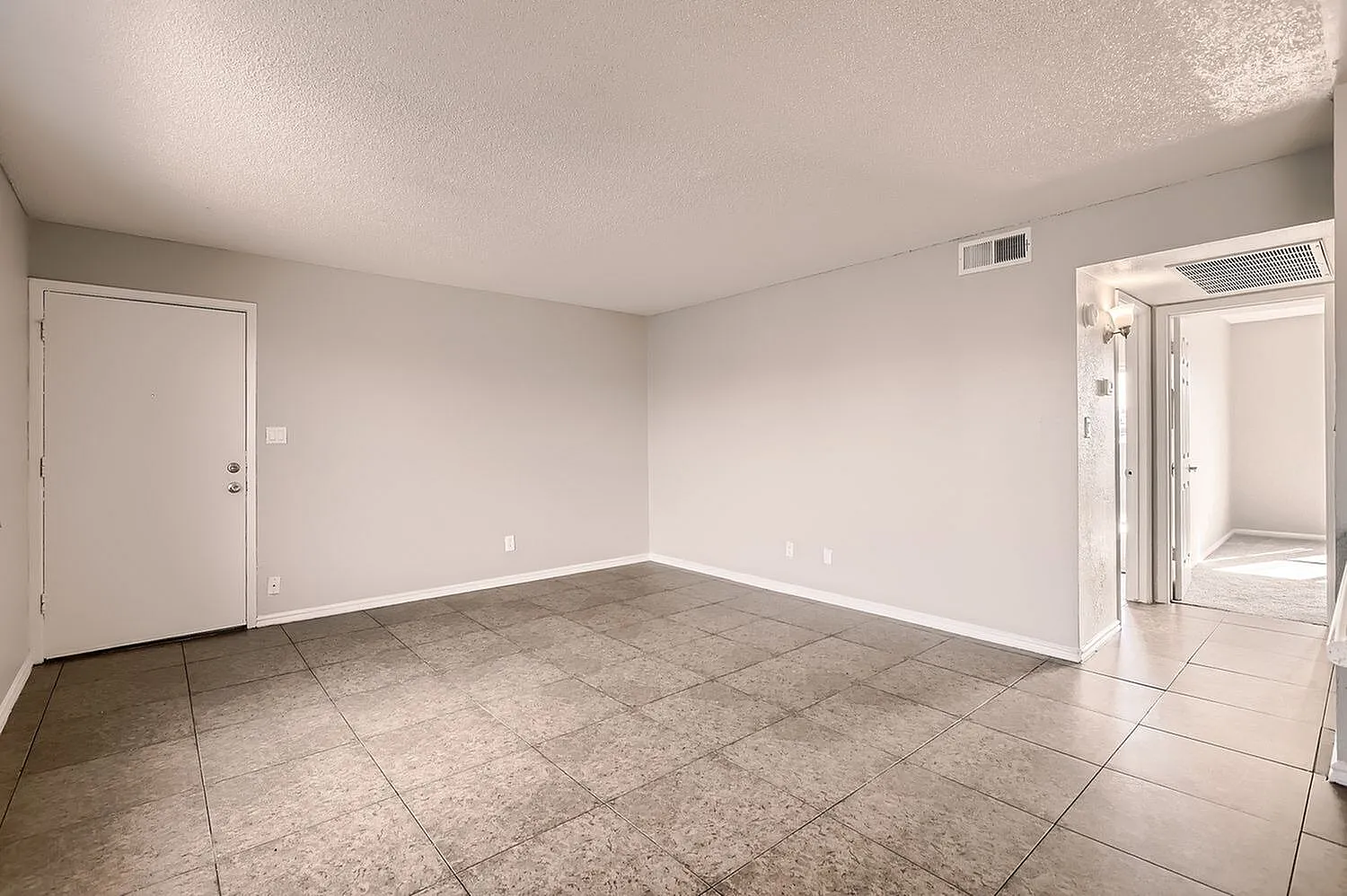 Living room, tile flooring, white walls, entry door