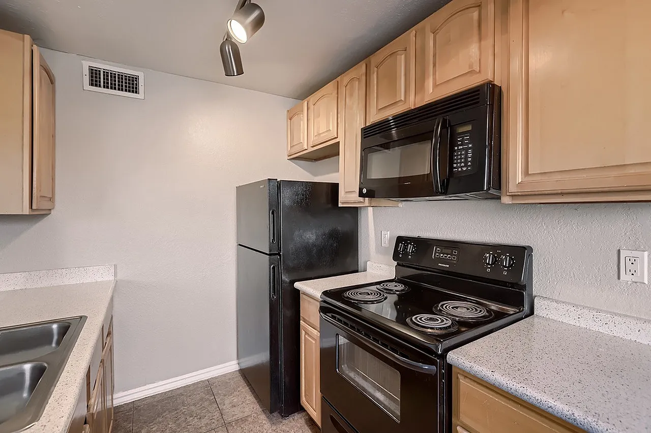 Kitchen, light wood cabinetry, black appliances, quartz countertops, wood-style plank flooring