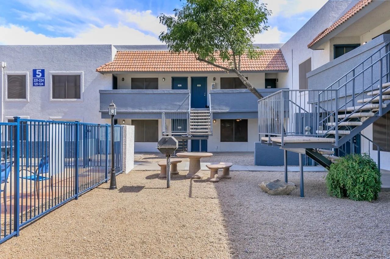 Courtyard with picnic table, blue metal fencing, modern buildings, tree
