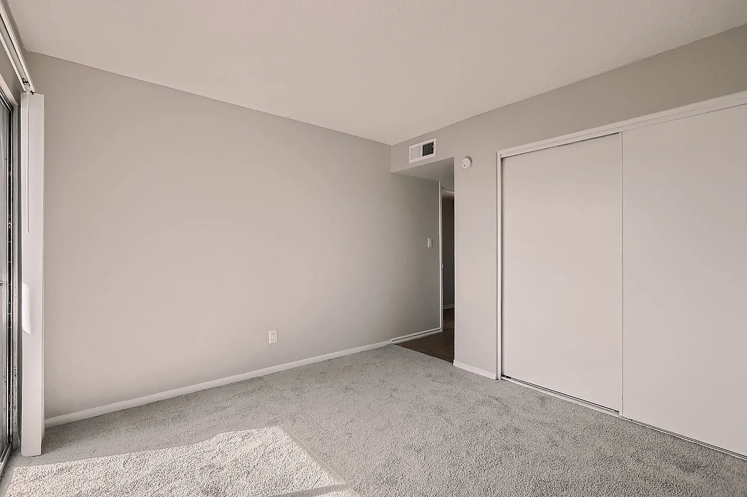 Bedroom, neutral walls, carpet flooring, sliding closet doors, ceiling vent