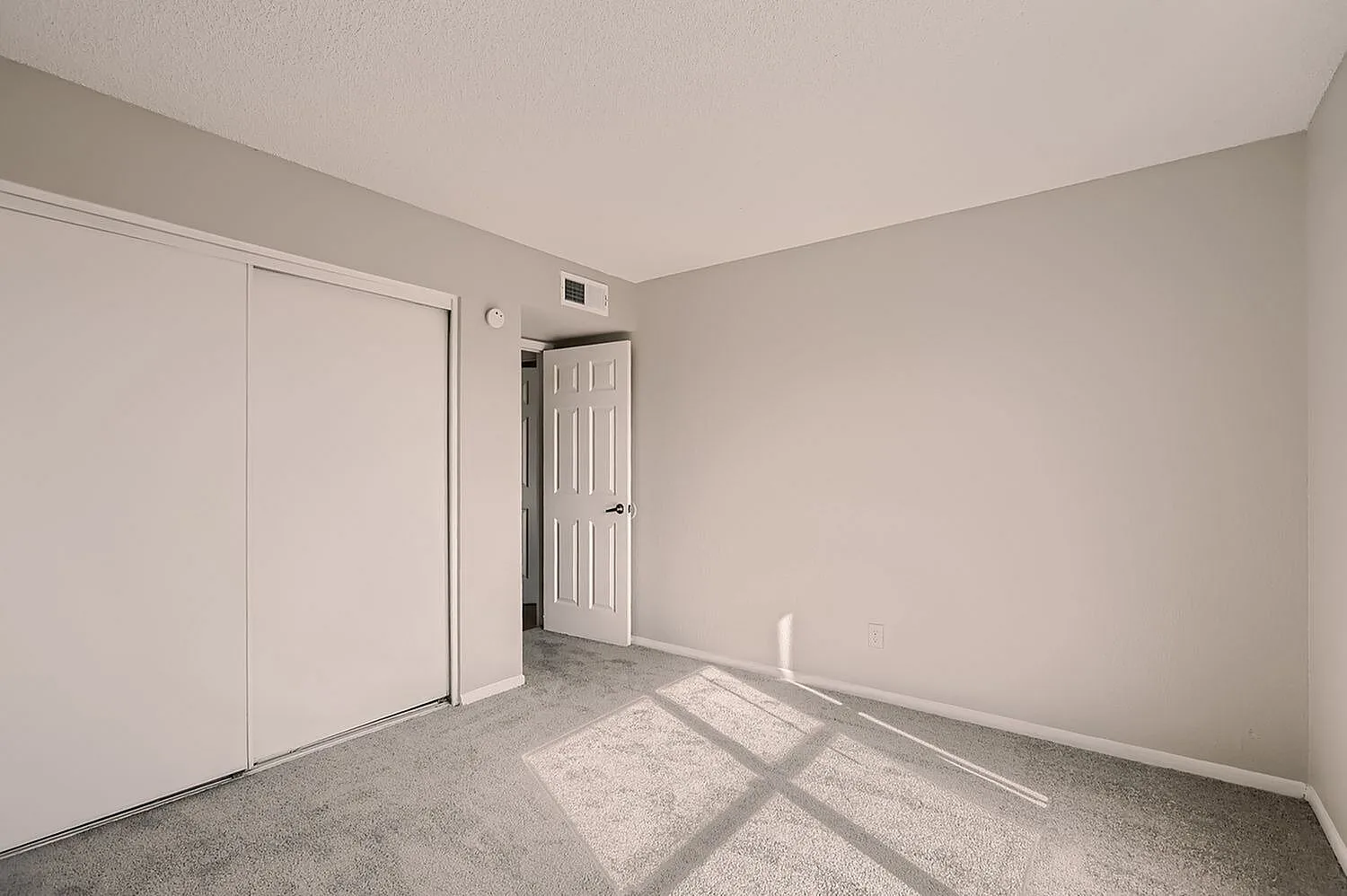 Bedroom, gray carpeting, white sliding closet doors, interior door, neutral walls