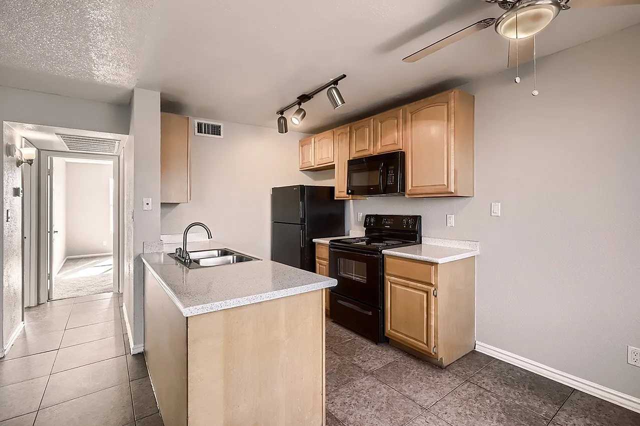 Kitchen, light wood cabinetry, white quartz countertops, black appliances, wood-style plank flooring