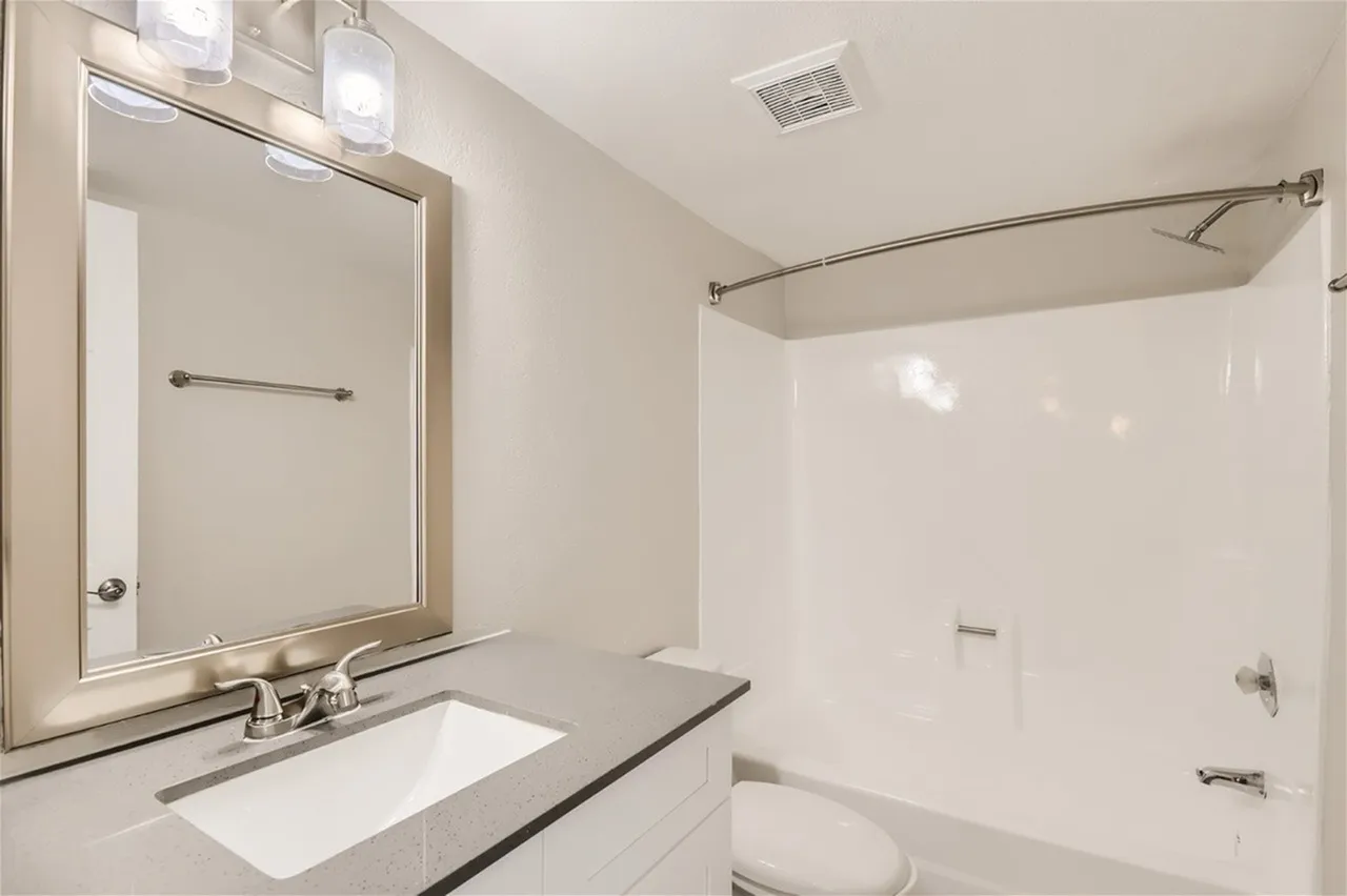 Bathroom, white subway tile surround, quartz countertop, chrome fixtures, mirror with lighting