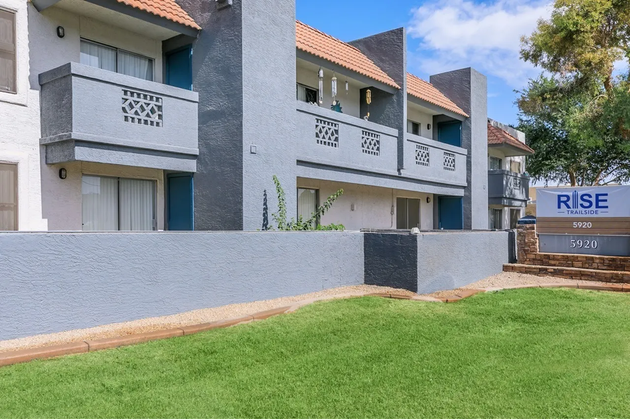 Contemporary multi-unit residential building, white and gray facade, geometric railing details, manicured lawn, terracotta roof tiles