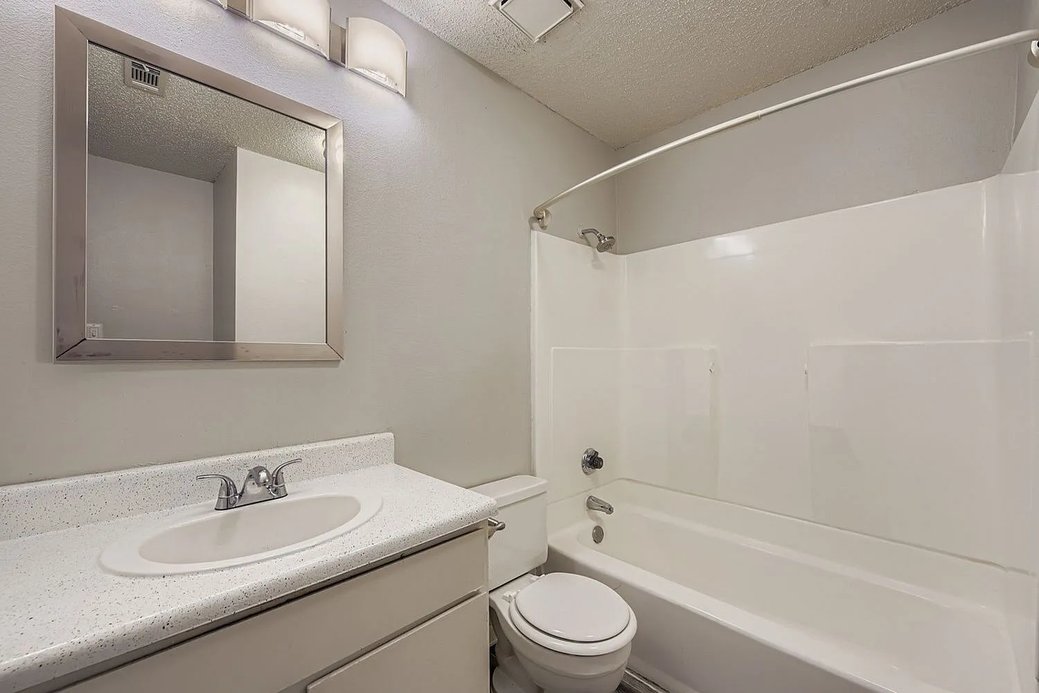Bathroom, white vanity with quartz countertop, mirrored medicine cabinet, white subway tile surround tub