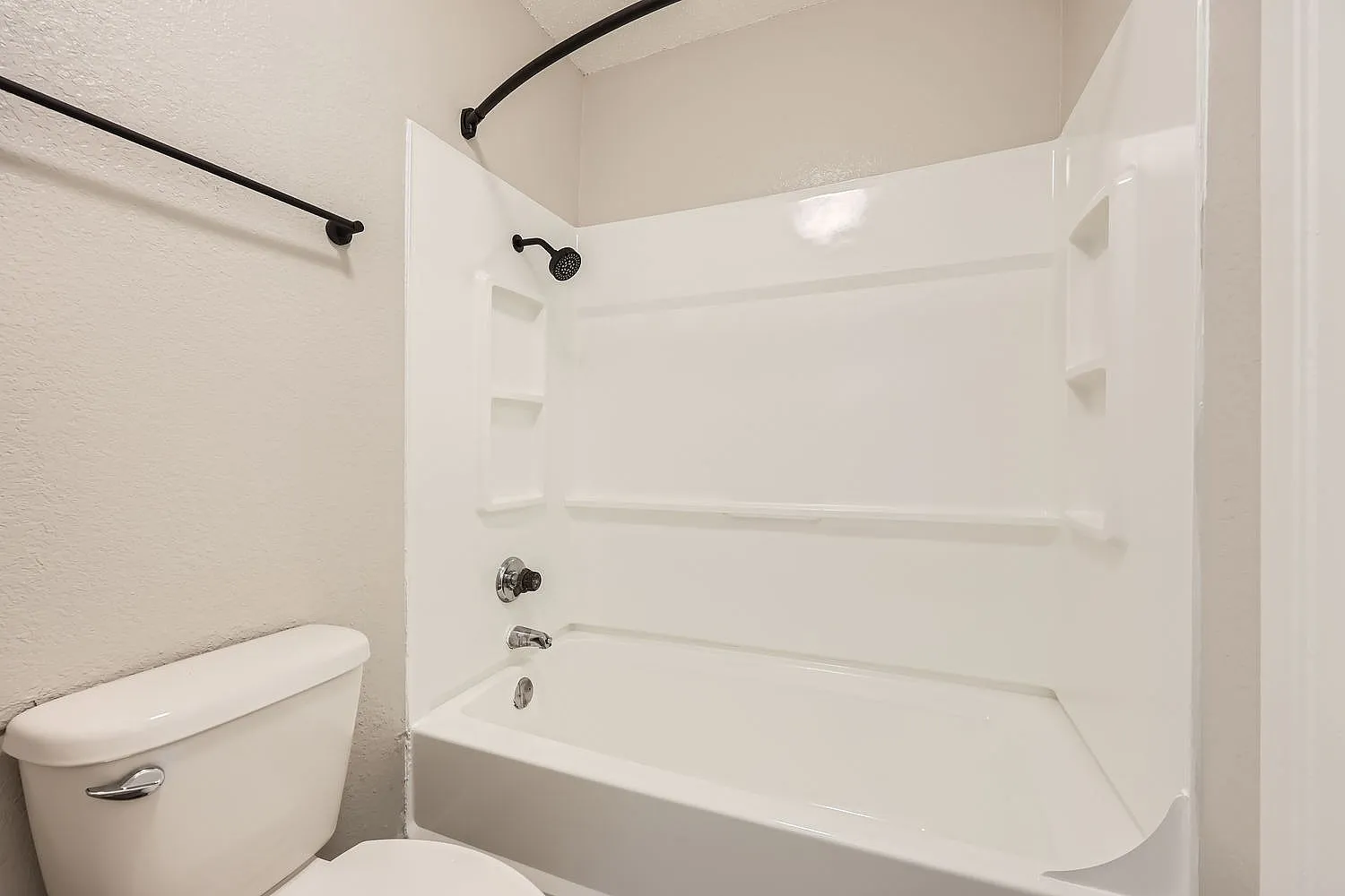 Bathroom, white toilet, white bathtub with shower enclosure, chrome fixtures, black shower rod