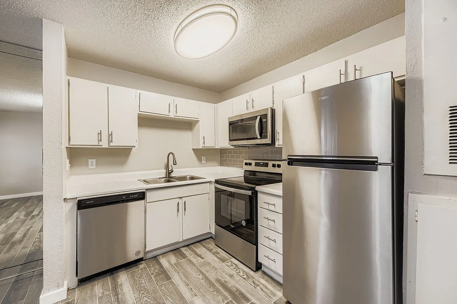 Kitchen, white shaker cabinetry, stainless steel appliances, wood-style plank flooring