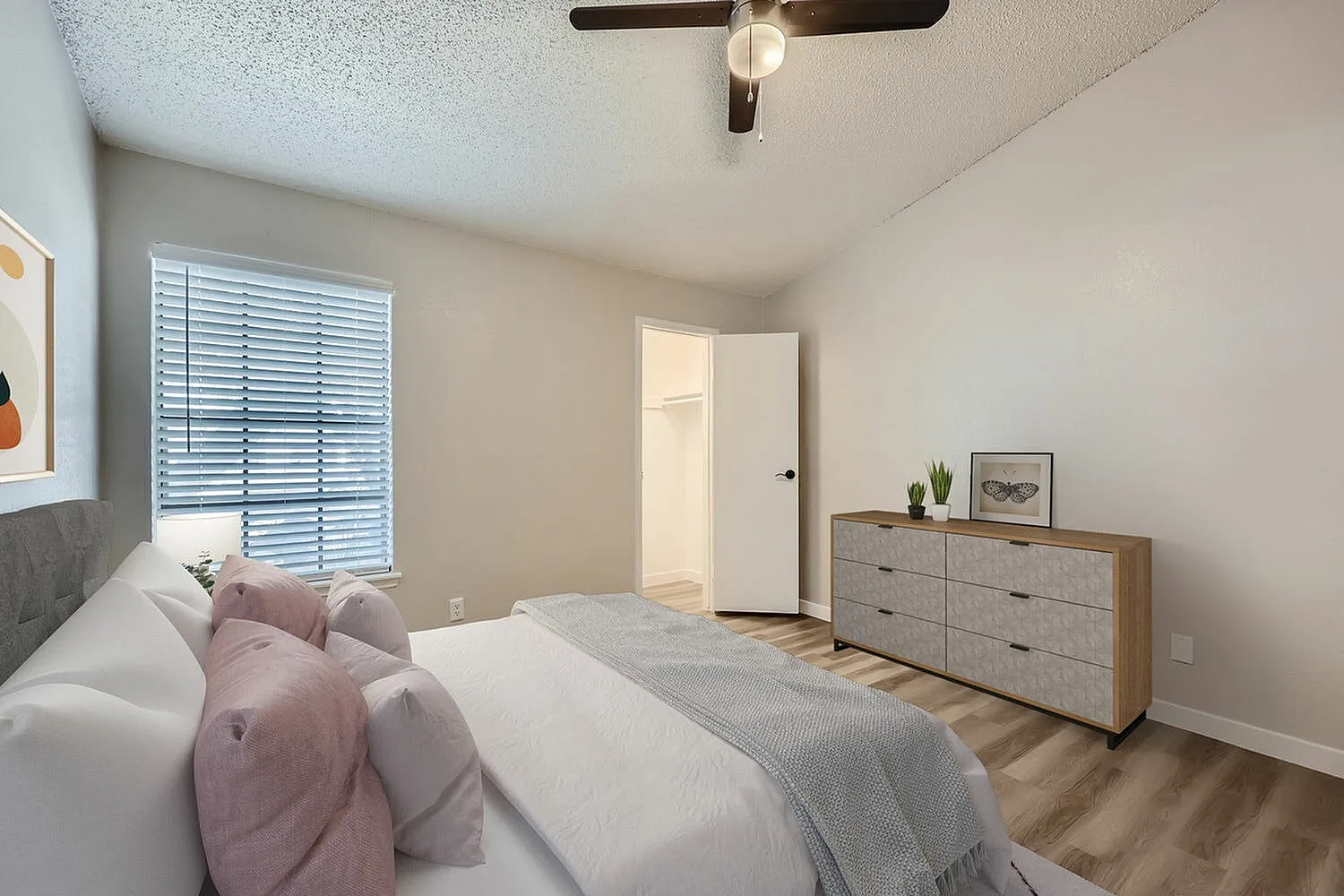 Primary bedroom, wood-style plank flooring, ceiling fan, window with shutters, dresser